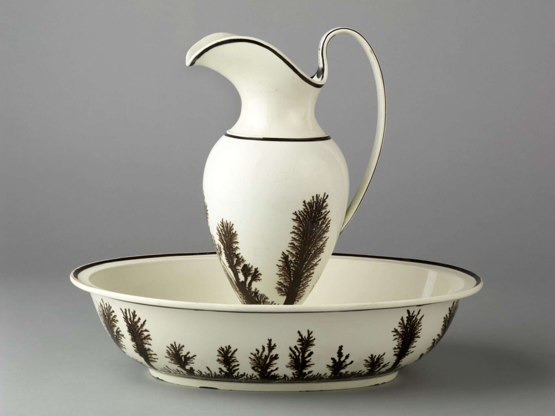 a jug with seaweed patterns inside of a bowl with similar patterns