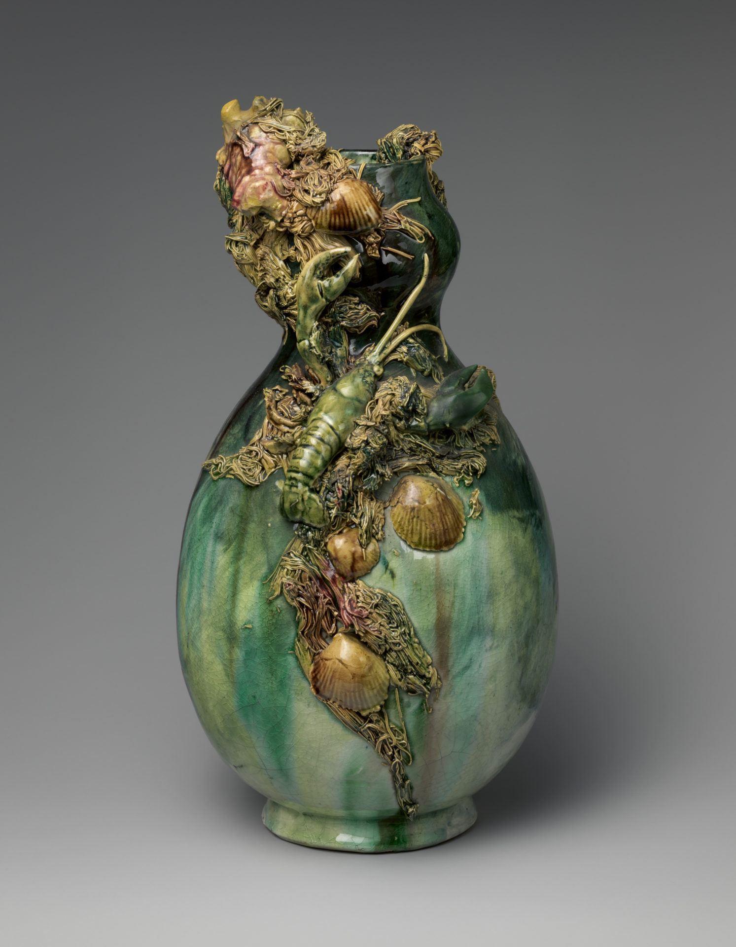 A green earthenware vase with marine animals such as lobsters and scallops embellished.