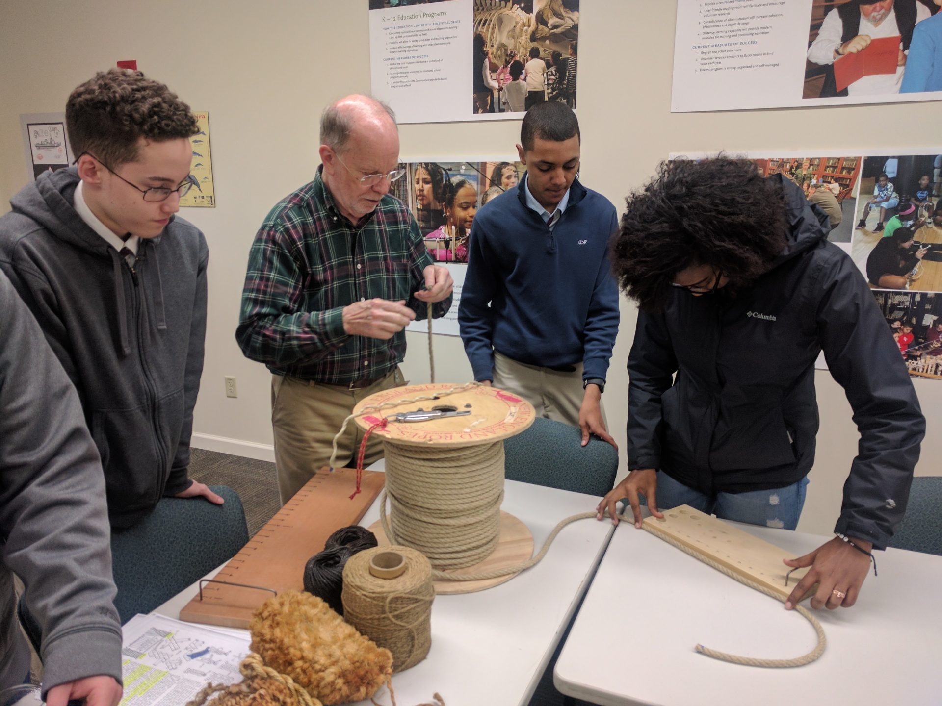 A group of apprentices work with a docent measuring rope.