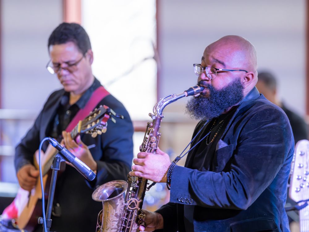 Kabujazz Ensemble Musician playing saxophone with a guitarist performing beside him on stage.