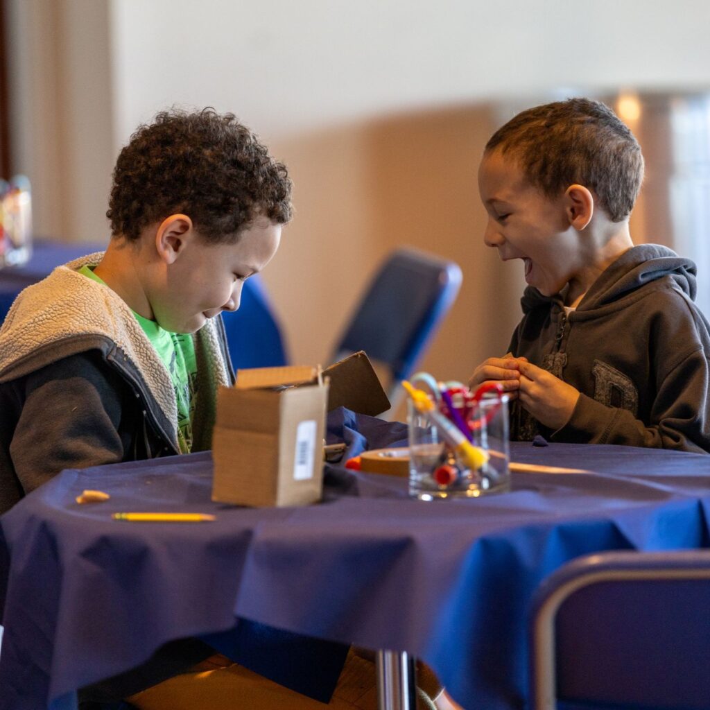 Two children excitedly crafting at a table in the Whaling Museum.
