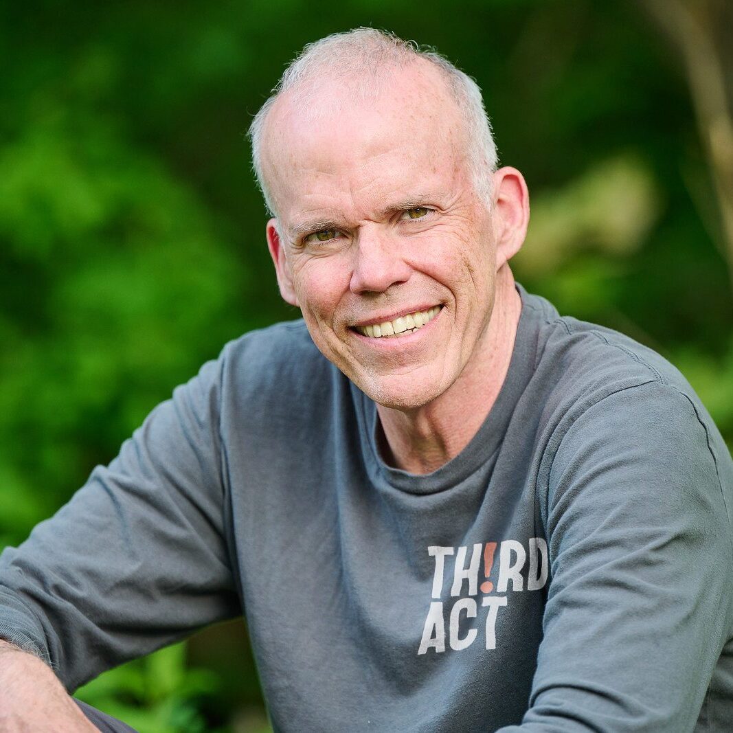 Bill McKibben Portrait of Bill McKibben smiling outdoors in a gray Third Act shirt.